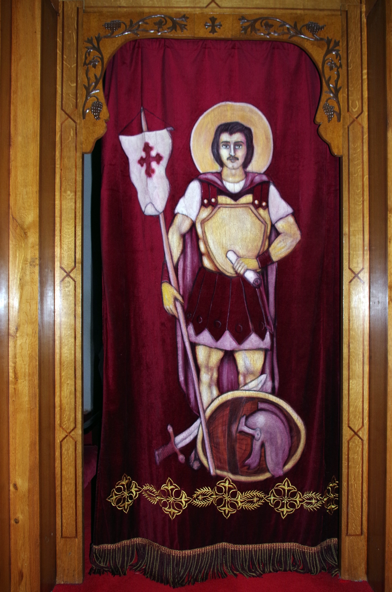 Purpurfarbener Samtvorhang mit aufgesticktem Heiligen Minas, dem der Altar dahinter geweiht ist.